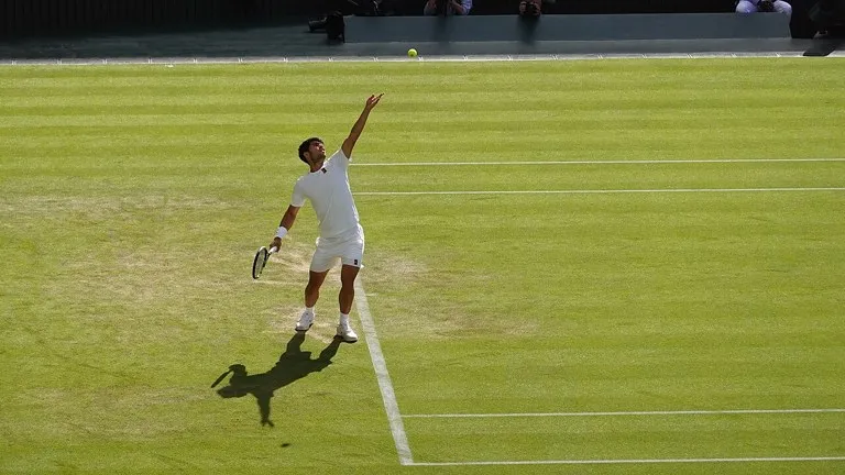 Carlos Alcaraz en pleno saque sobre la hierba de Wimbledon; Alcaraz a la final de Viena tras vencer a Medvedev