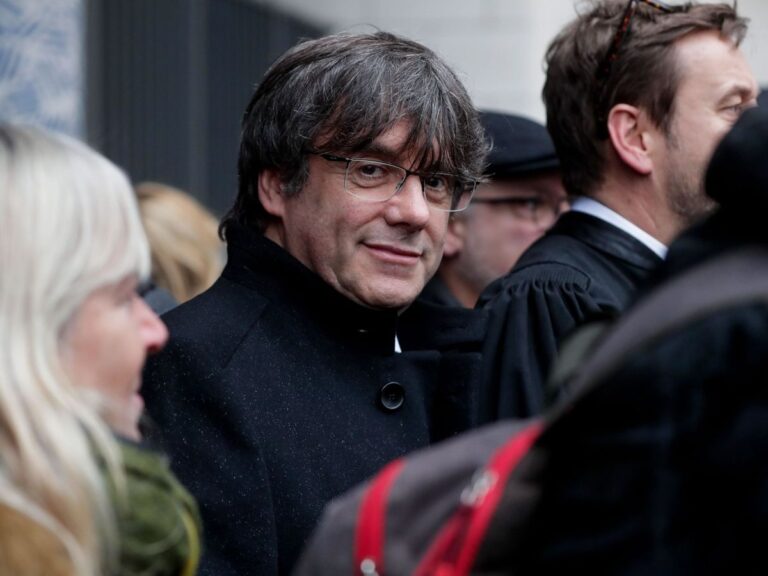 Amnistía a Puigdemont: el expresidente catalán Carles Puigdemont, de abrigo oscuro y gafas, rodeado de acompañantes en una comparecencia pública