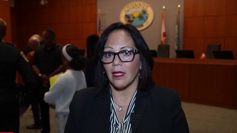 Jackie Espinosa, alcaldesa de Kissimmee, hablando en la sede municipal con el sello de la ciudad al fondo