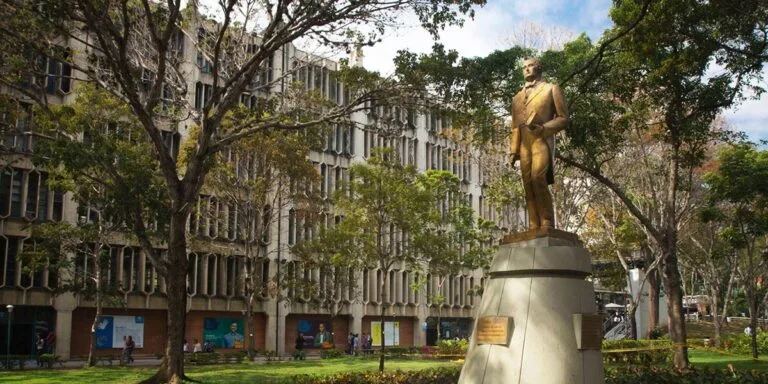 Becas universitarias Venezuela: campus de una universidad venezolana con su estatua y jardines