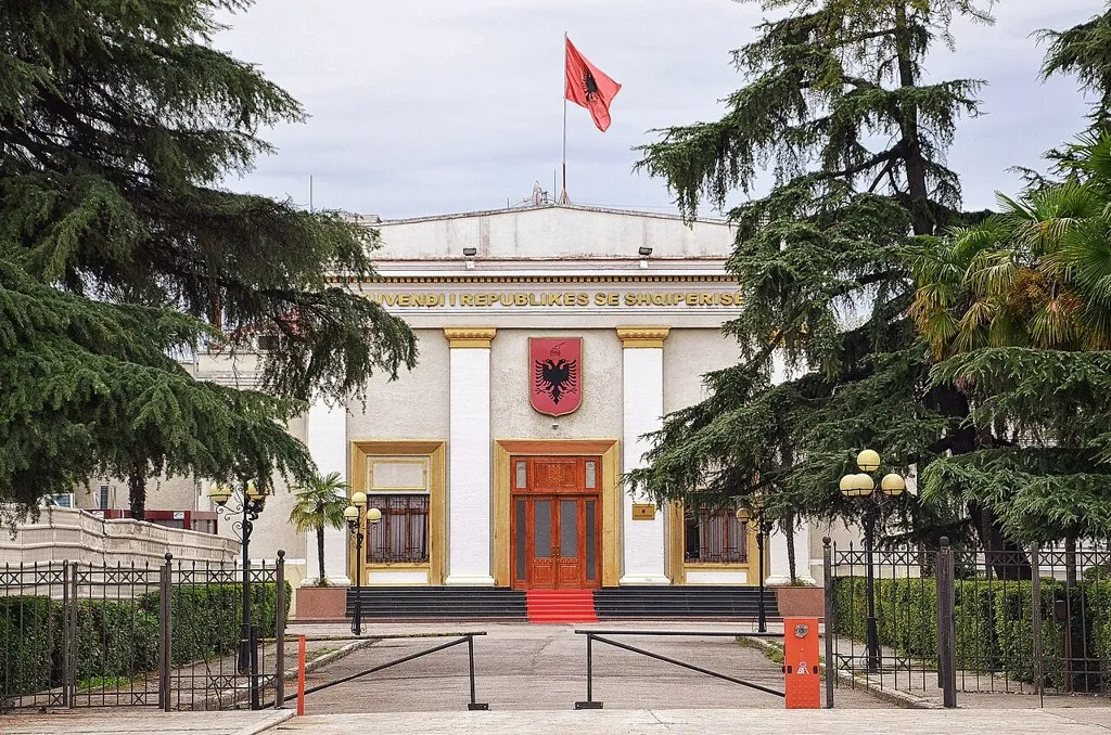Parlamento de Albania: fachada de la Asamblea en Tirana con la bandera albanesa