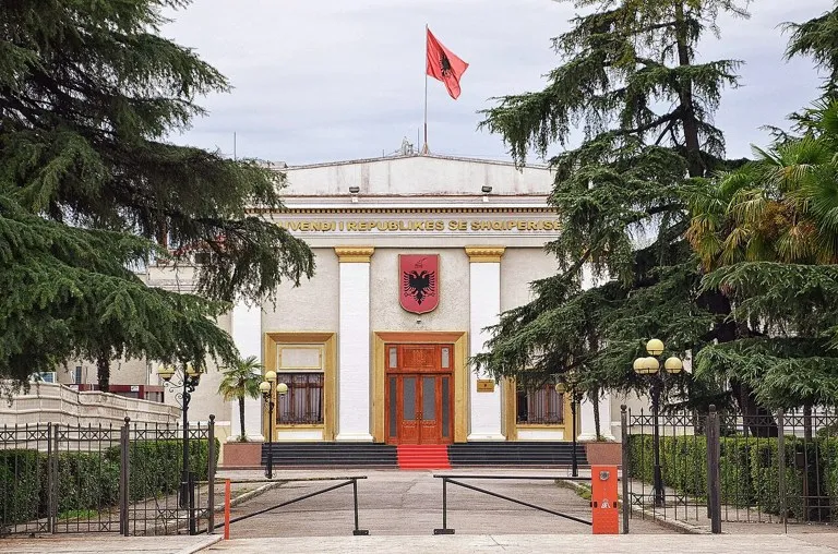 Parlamento de Albania: fachada de la Asamblea en Tirana con la bandera albanesa