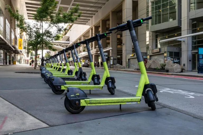 Bicicletas y patinetas eléctricas: fila de patinetas eléctricas de alquiler en una calle de la ciudad