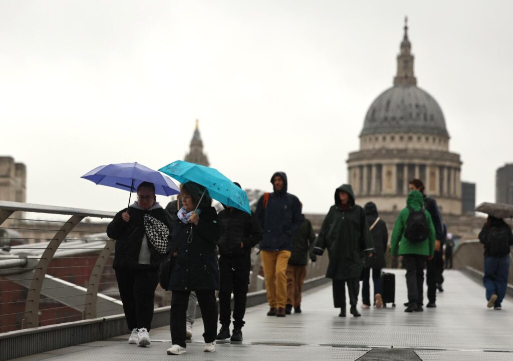 Borrasca Austen: peatones con paraguas cruzan un puente de Londres bajo la lluvia, con la catedral de San Pablo al fondo