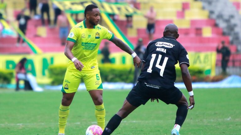 Bucaramanga 1-1 América de Cali: un jugador del Atlético Bucaramanga, con el uniforme auriverde, protege el balón ante Mina, del América de Cali, en el estadio Américo Montanini por la fecha 15 de la Liga BetPlay