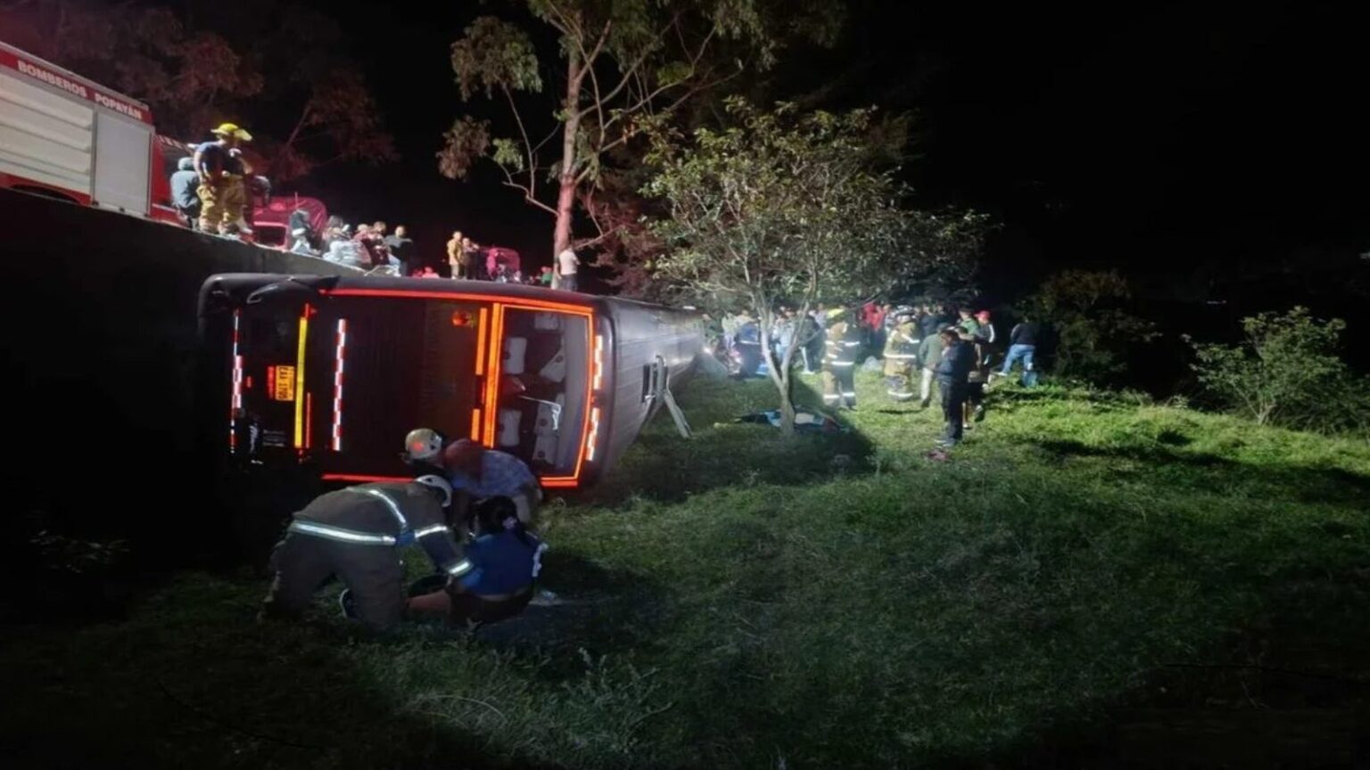 bus en la Panamericana volcado en una cuneta entre Timbío y Rosas, Cauca, mientras bomberos de Popayán atienden a los heridos de madrugada