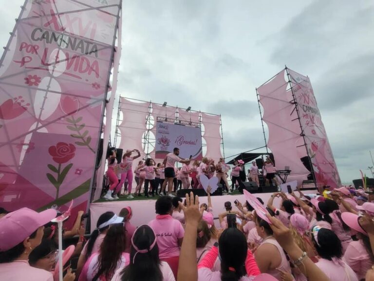 Participantes de rosa frente a la tarima de la Caminata por la Vida de FAMAC en Maracaibo, bajo el cartel de la edición XXVI de la marcha
