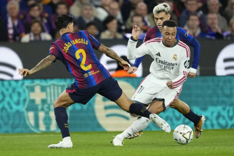 China suspende LaLiga: Kylian Mbappé, con la camiseta del Real Madrid, disputa el balón ante João Cancelo, del Barcelona, en un partido de la Liga española