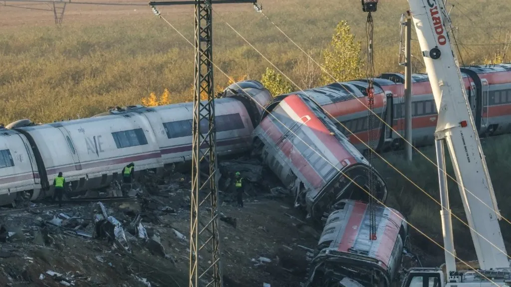 Choque de trenes en Toledo: una grúa trabaja sobre los vagones descarrilados del AVE y el Iryo junto a la vía en Urda