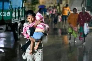 ciclón Arnab en India: mujer carga a un niño bajo la lluvia durante la evacuación en Kakinada, Andhra Pradesh