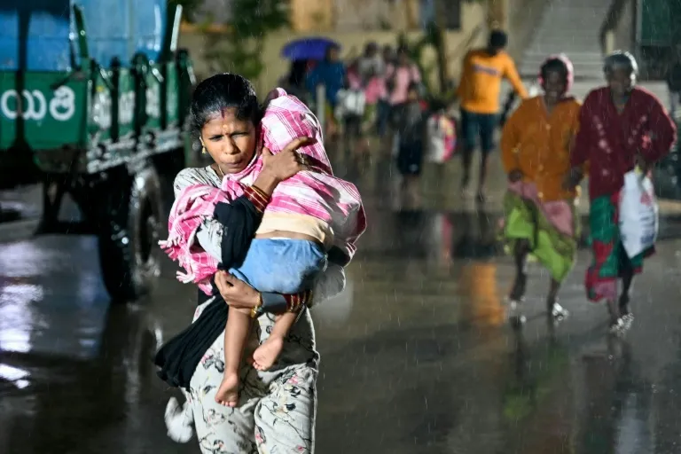 ciclón Arnab en India: mujer carga a un niño bajo la lluvia durante la evacuación en Kakinada, Andhra Pradesh