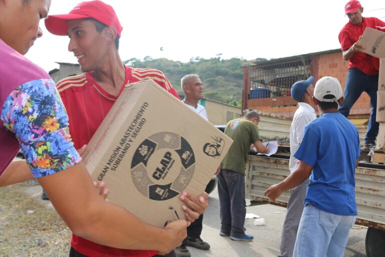 Los CLAP como instrumento de control electoral: un voluntario carga una caja del programa de alimentos durante una jornada de distribución en Venezuela