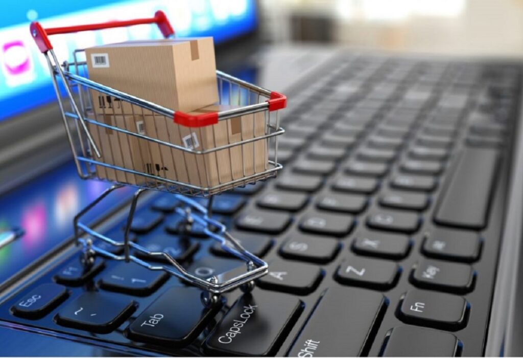 Un carrito de compras con cajas sobre el teclado de una laptop ilustra el crecimiento del comercio electrónico venezolano