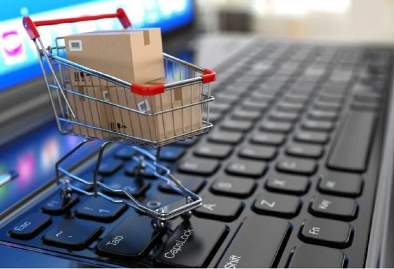 Un carrito de compras con cajas sobre el teclado de una laptop ilustra el crecimiento del comercio electrónico venezolano