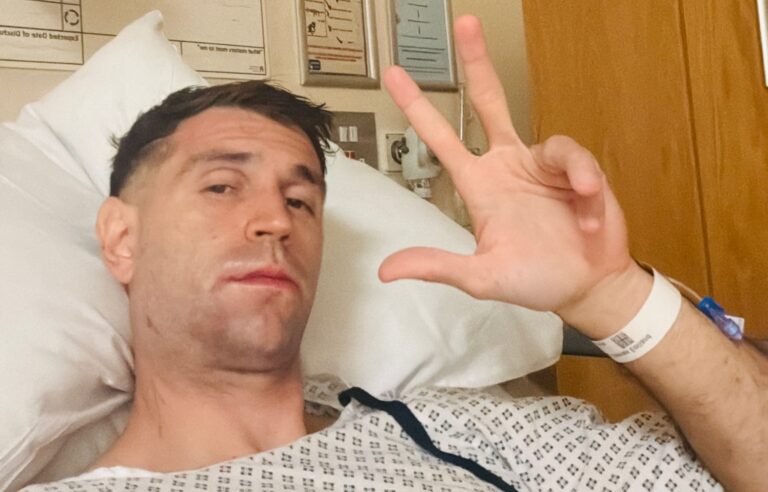 Emiliano Dibu Martínez en la cama del hospital, con bata clínica y pulsera de paciente, tras su operación: Dibu Martínez fractura de mandíbula
