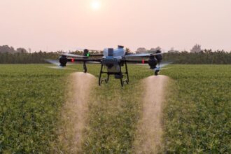 Dron agrícola en pleno vuelo aplicando insumos sobre un cultivo, ejemplo del uso de drones en Venezuela