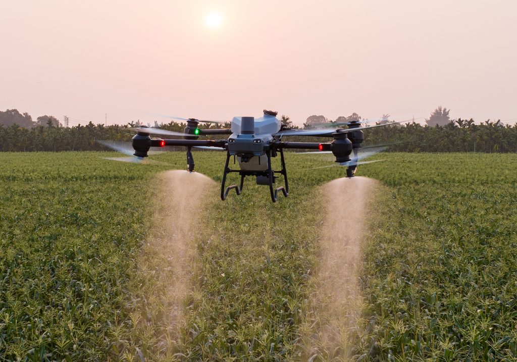 Dron agrícola en pleno vuelo aplicando insumos sobre un cultivo, ejemplo del uso de drones en Venezuela