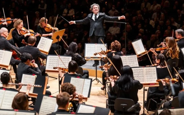 Gira europea de Dudamel con la New York Philharmonic: el director venezolano dirige a la orquesta con los brazos en alto ante el público