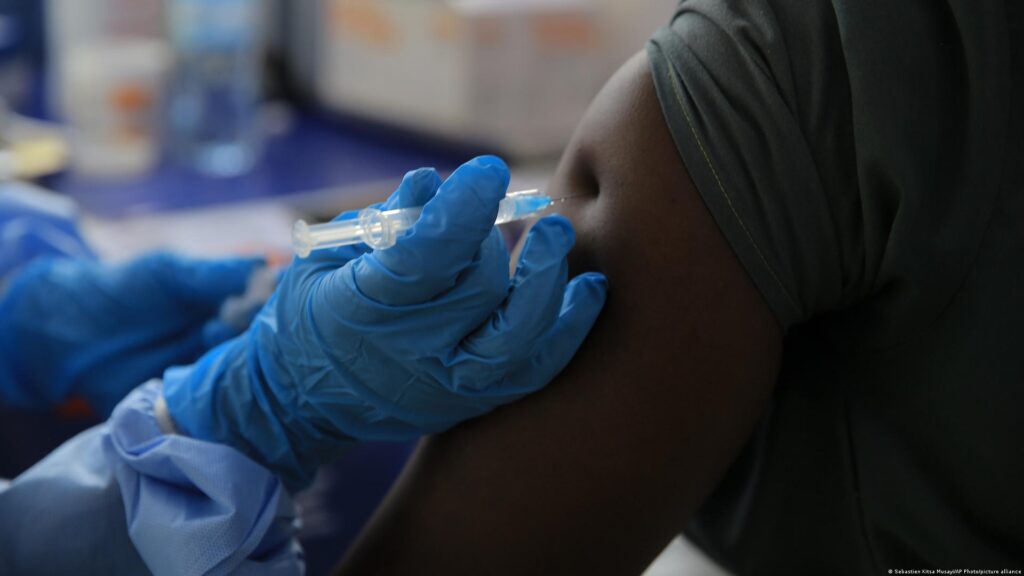 Ensayo de vacuna contra el ébola en RD Congo: un sanitario con guantes azules aplica una inyección en el brazo de un participante