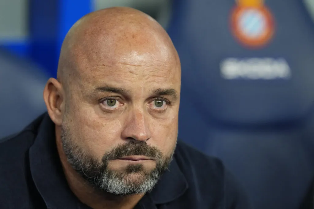 Espanyol destituye a Manolo González: el entrenador, en primer plano, con el escudo del club en el banquillo
