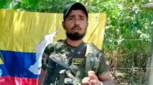 Extradición del Mocho Olmedo: Willinton Henao Gutiérrez, alias el Mocho Olmedo, con indumentaria de las disidencias de las Farc frente a una bandera de Colombia