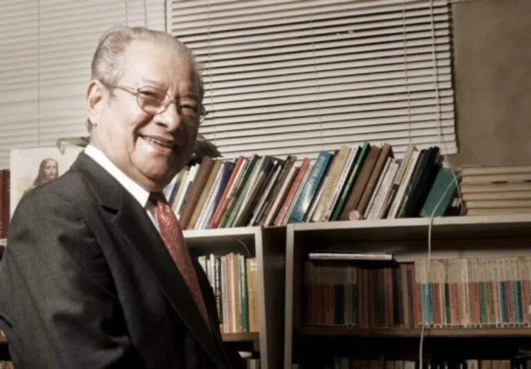 Tito Balza Santaella sonríe frente a los libros de su biblioteca, en una fotografía de archivo