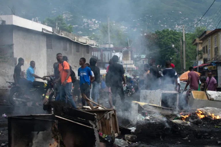 Familias desplazadas en Haití: barricada ardiendo y manifestantes en una calle de Puerto Príncipe