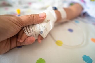 Mano de un adulto sostiene la mano vendada de un niño hospitalizado, imagen ilustrativa del niño herido en Bucaramanga durante su atención médica