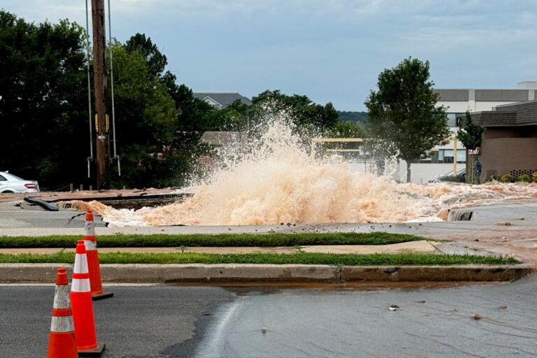 Agua brotando a chorros de una tubería principal rota que inundó una calle, imagen del cierre de USA Parkway