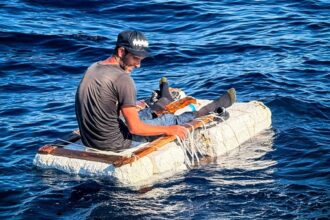 Migrante cubano sentado sobre una balsa improvisada de espuma y madera frente a la costa de Florida