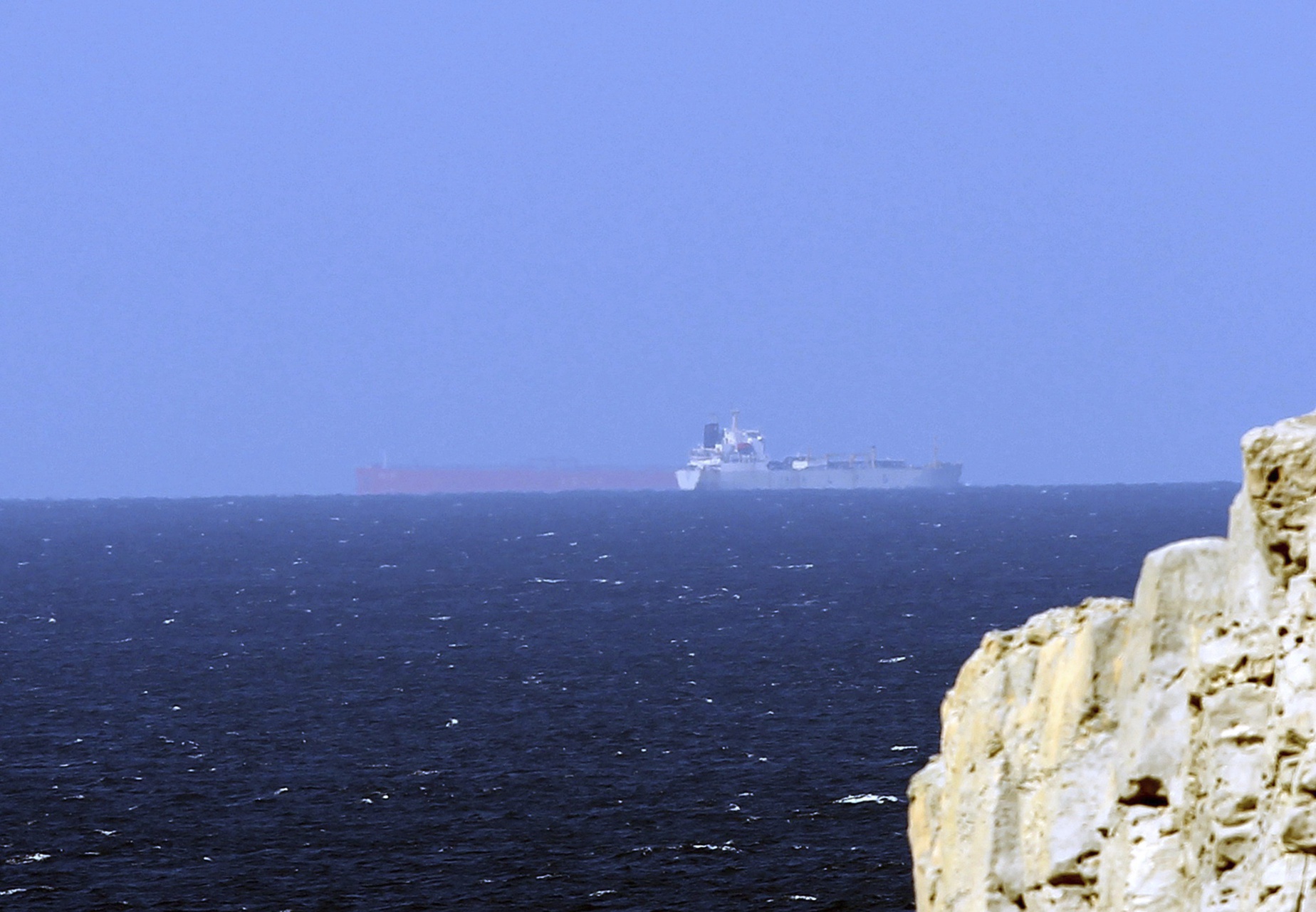 Superpetrolero en el estrecho de Ormuz: un buque navega a lo lejos junto a la costa rocosa del paso marítimo