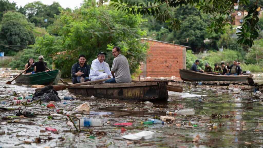 Inundaciones en Paraguay por El Niño: una familia se desplaza en canoa por una calle inundada de Ciudad del Este tras la crecida del río Paraná