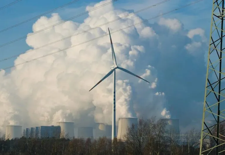 Gases de efecto invernadero: un aerogenerador frente a las torres de refrigeración de una central que emite grandes nubes de vapor