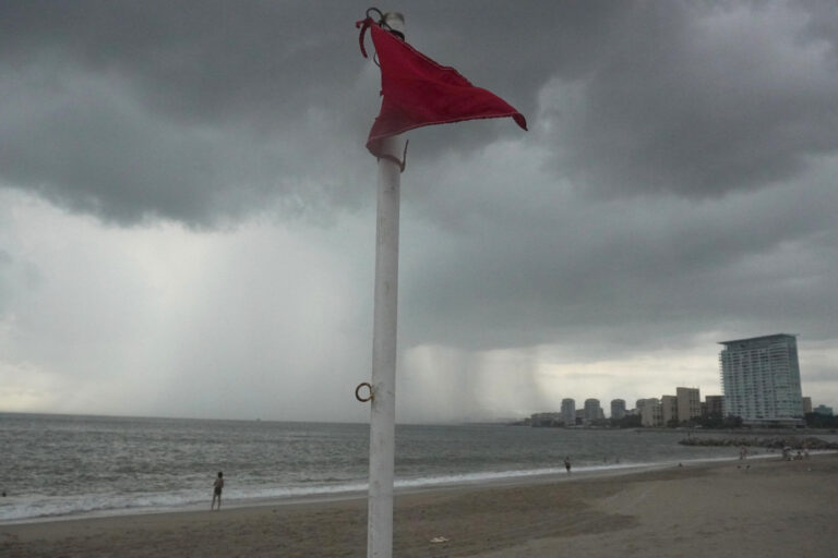 Bandera roja de alerta en una playa del Pacífico mexicano bajo nubes de tormenta por el huracán Vance