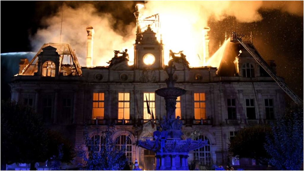 Ayuntamiento de Limoges en llamas durante la noche, con bomberos trabajando sobre el tejado del monumento histórico