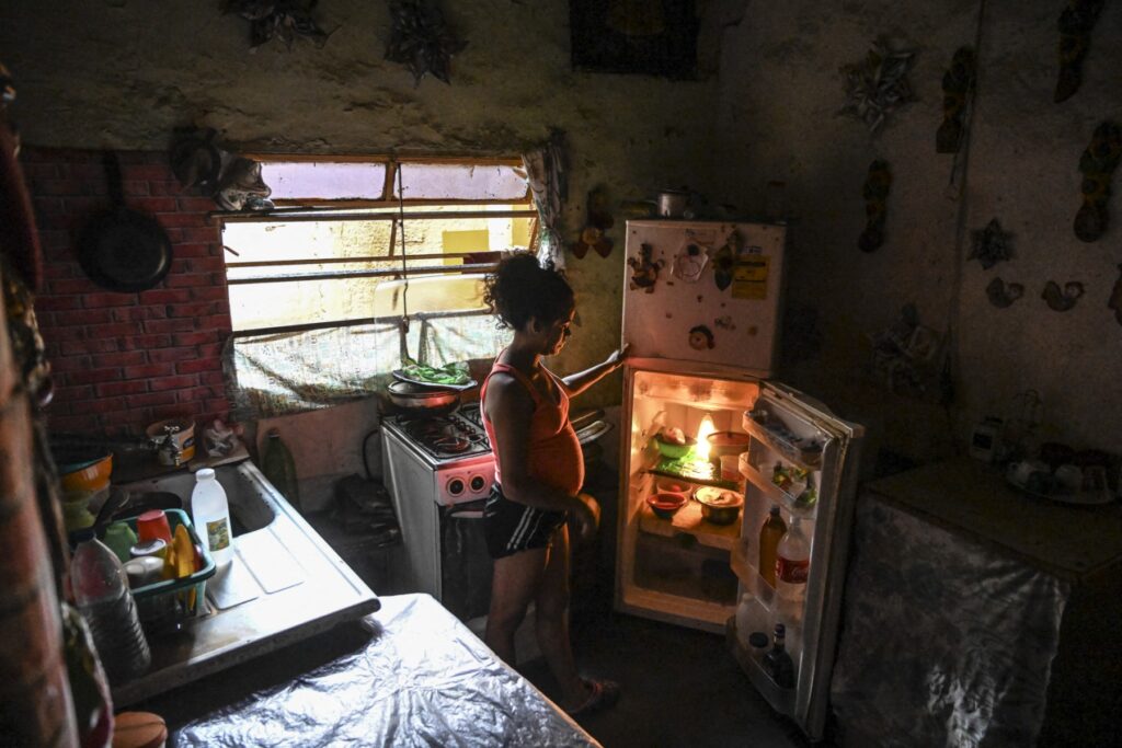 Inseguridad alimentaria en Venezuela: una mujer embarazada abre una nevera casi vacía en la cocina de su casa