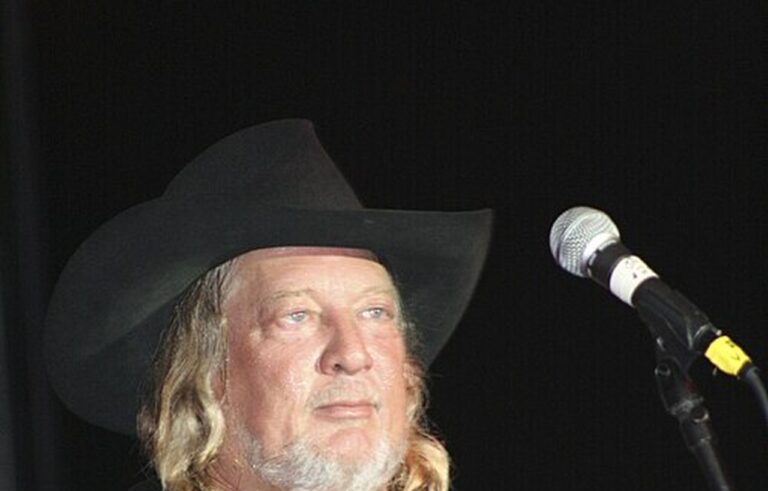 John Anderson con sombrero vaquero y guitarra durante una actuación en directo