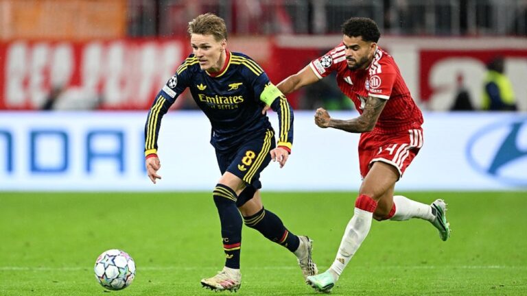 Luis Díaz con el uniforme rojo del Bayern Múnich disputando el balón con Martin Ødegaard del Arsenal en la Champions League