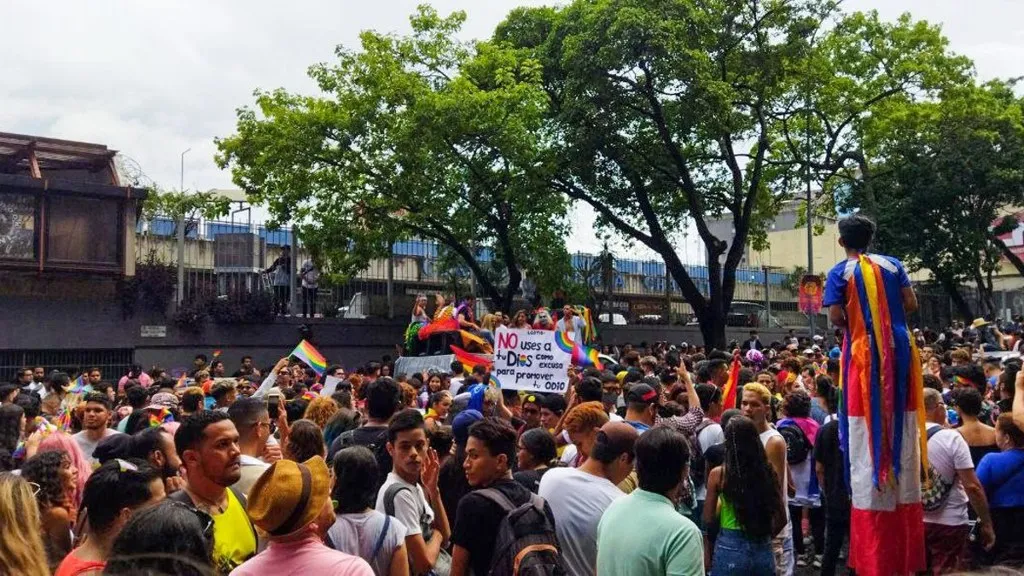 Multitud en la Marcha del Orgullo en Chacaíto, Caracas, con banderas arcoíris durante la concentración en la Plaza Brión