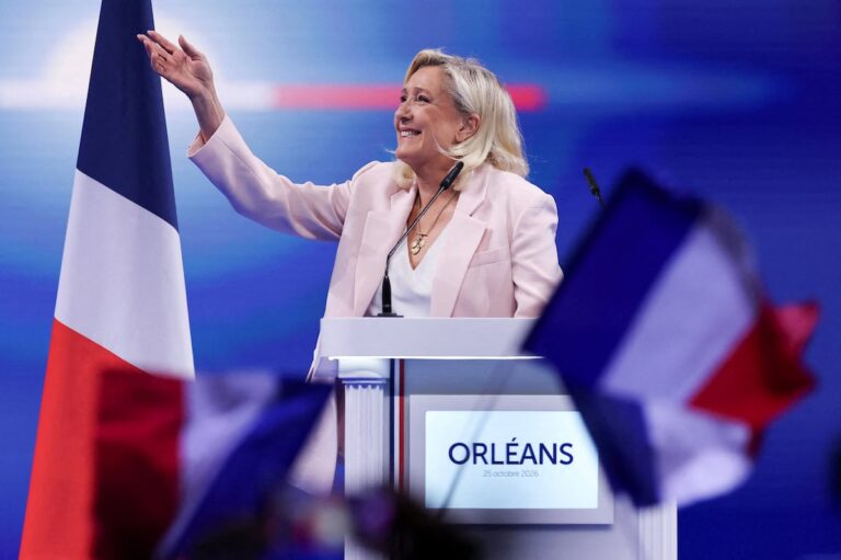 Marine Le Pen lanza su candidatura presidencial: la líder de Agrupación Nacional saluda desde el atril en el mitin de Orleans, con la fecha 25 de octubre de 2026