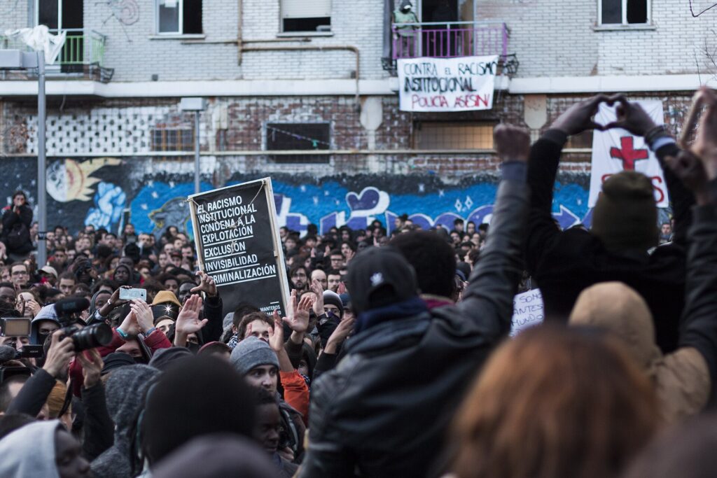 Multitud en una concentración contra el racismo en Madrid, con una pancarta contra el racismo institucional, en el marco de las movilizaciones contra el racismo en España