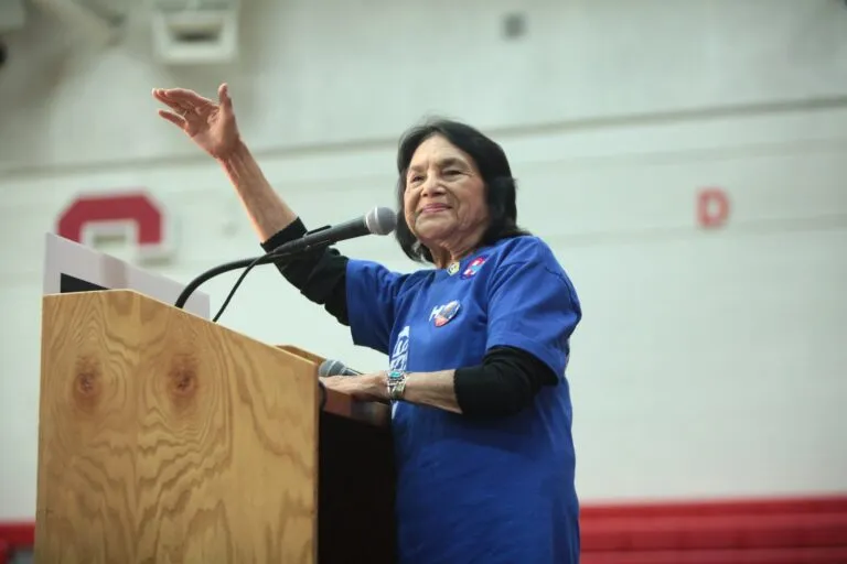 Dolores Huerta habla desde un atril con el brazo alzado durante un acto público en Phoenix, Arizona