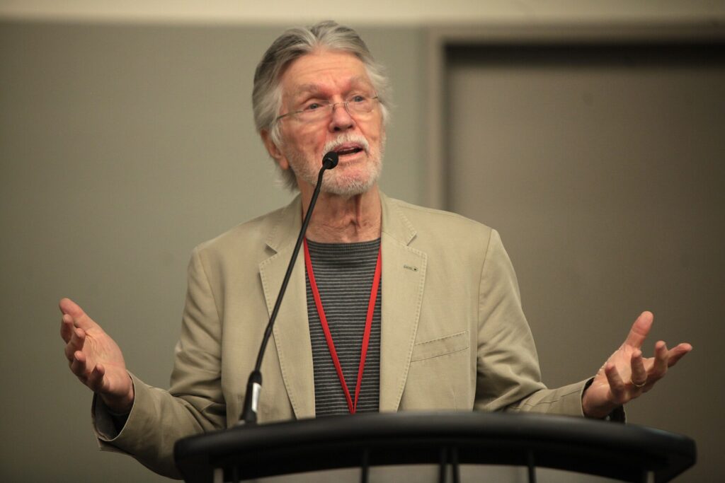 Tom Skerritt hablando ante un micrófono en un panel en 2014
