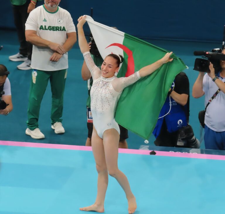 Nemour oro en barra de equilibrio: Kaylia Nemour celebra con la bandera de Argelia tras una final mundial de gimnasia