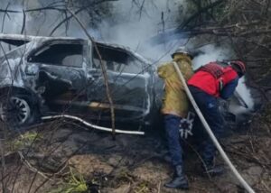 Camioneta calcinada del accidente en la vía Tacarigua-La Laguna de Barlovento mientras bomberos sofocan las llamas; en el vehículo viajaba el nieto de Hugo Chávez