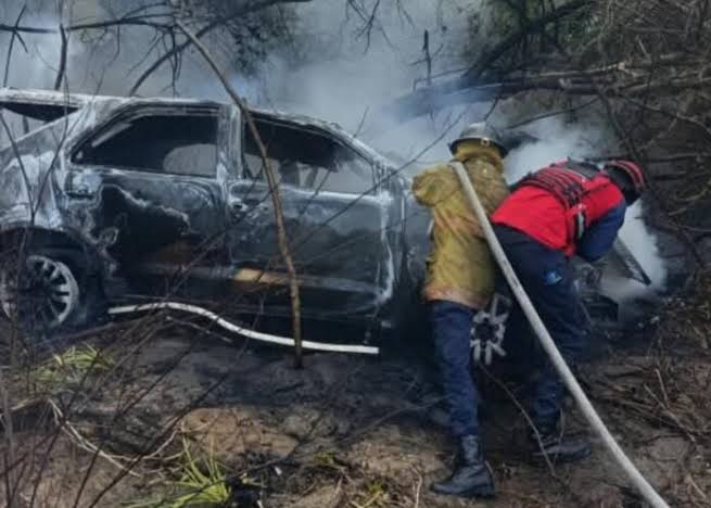 Camioneta calcinada del accidente en la vía Tacarigua-La Laguna de Barlovento mientras bomberos sofocan las llamas; en el vehículo viajaba el nieto de Hugo Chávez