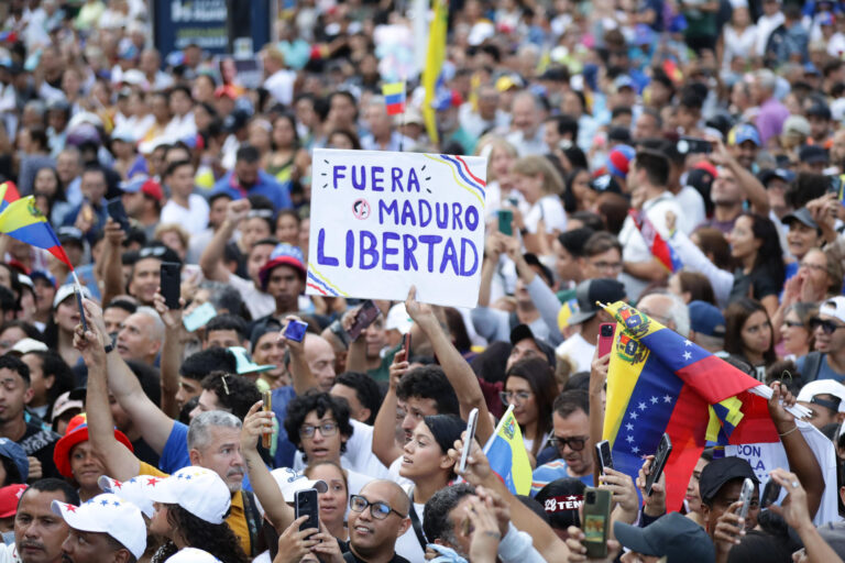 Protesta nacional Venezuela: multitud de simpatizantes opositores con banderas venezolanas y una pancarta que dice Fuera Maduro, libertad