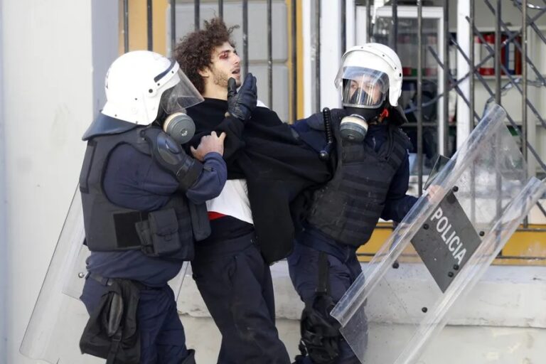 Protestas en Albania: dos policías antidisturbios detienen a un joven manifestante durante los disturbios en Tirana