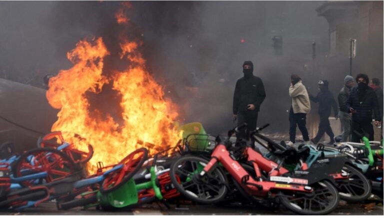 Manifestantes encapuchados junto a bicicletas en llamas durante las protestas en Francia, en París