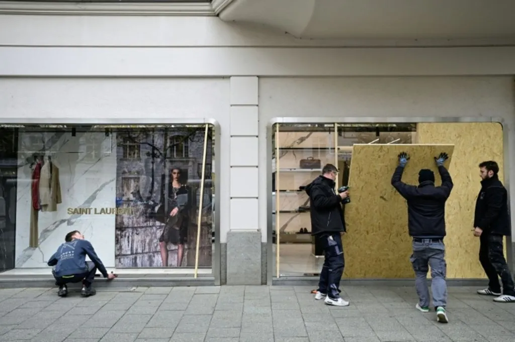 protestas juveniles en Alemania: obreros blindan con planchas de madera el escaparate de una tienda de lujo en Berlín ante la jornada de manifestaciones